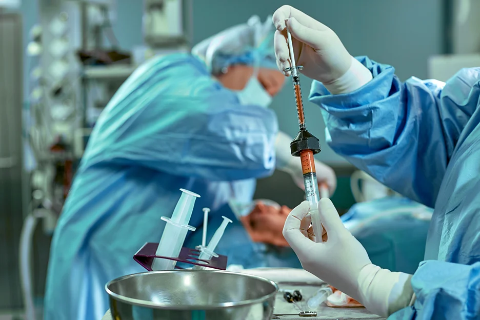 A group of surgeons holding a syringe with fat in an operating room.