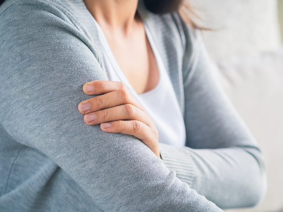 A woman is sitting on a couch showcasing perfectly sculpted arms.