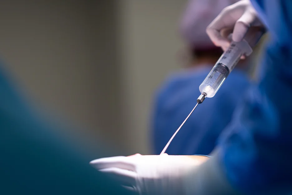A surgeon is using a syringe to inject a patient's arm.