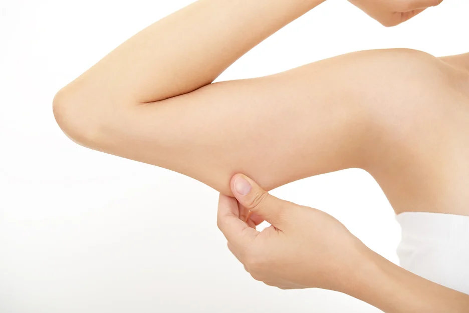 A woman is gently touching her arm.