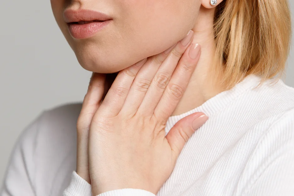 A woman is touching her chin and throat with her hands, possibly considering options like chin liposuction or Coolsculpting risks.