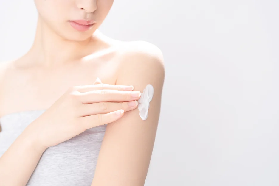A woman is applying topical cream after having fibrosis after arm liposuction.