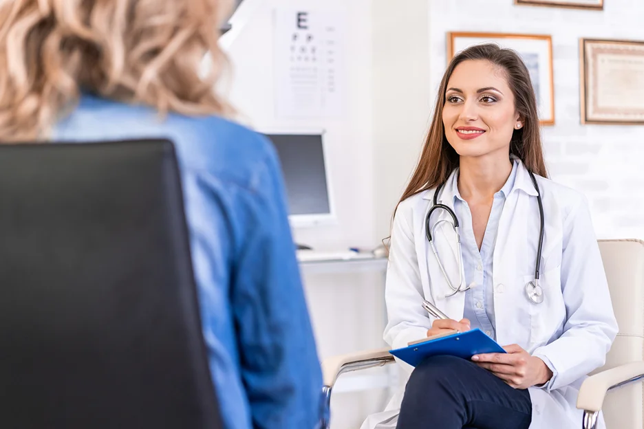 A female doctor is talking to a patient in an office, discussing arm liposuction options for achieving sleek arms.