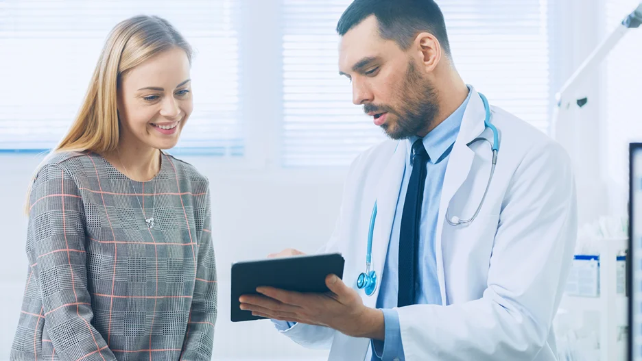 A doctor and a woman examining a tablet while discussing non-invasive arm lipo options.