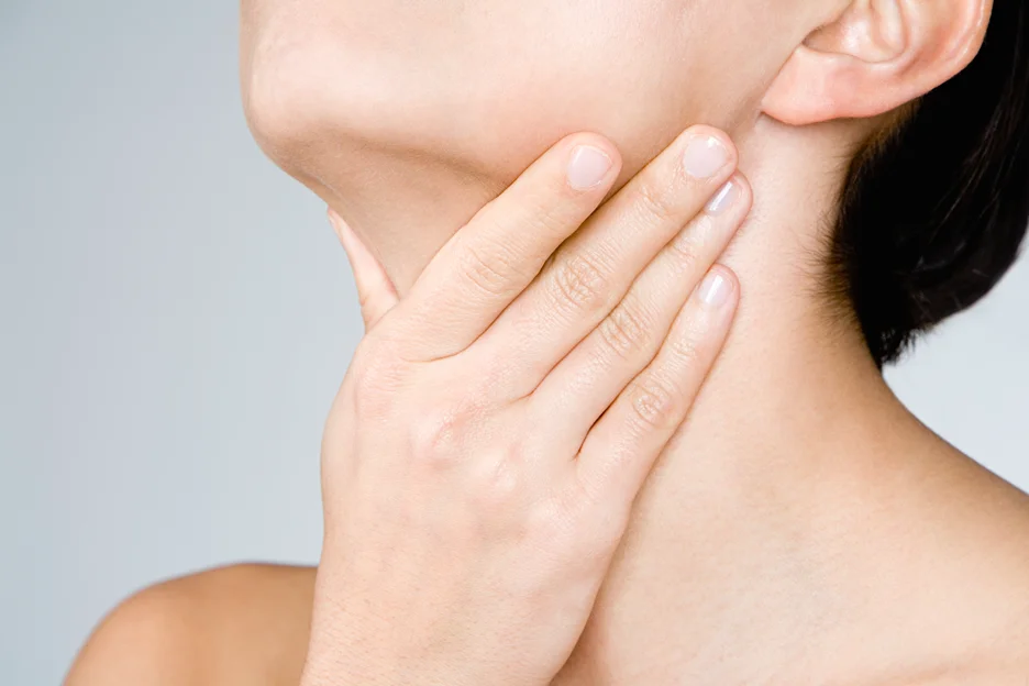 a woman touches her neck, examining swollen lymph nodes after chin lipo