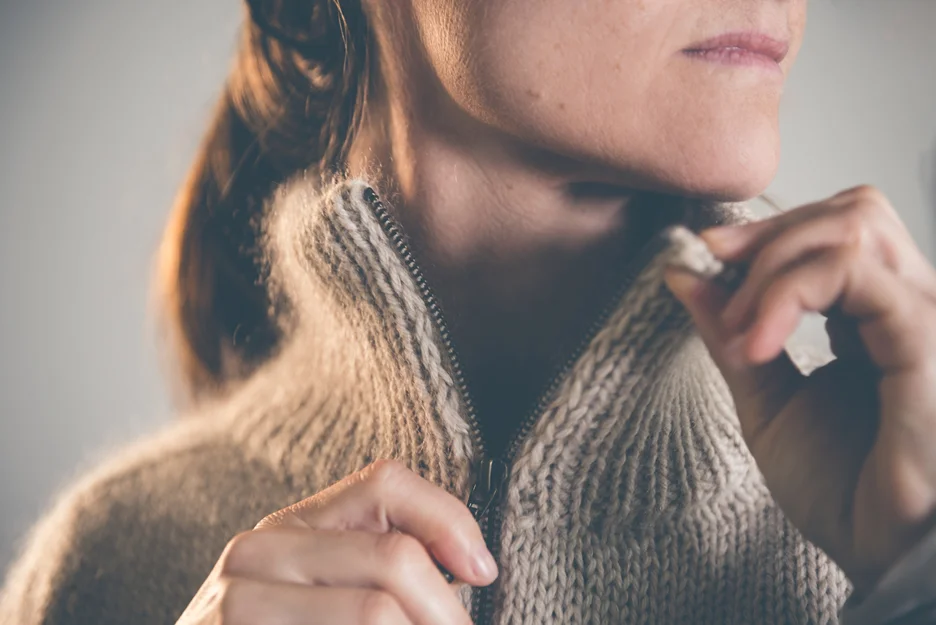 A woman is putting on a sweater, after having undergone VASER arm lipo.