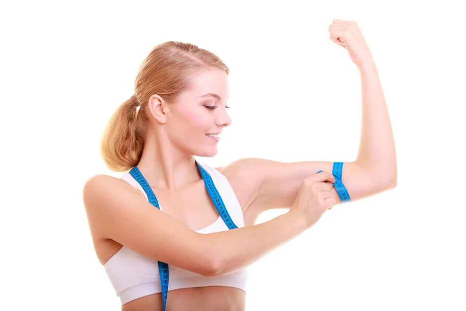A woman measuring her arm with a tape measure to reduce risks before brachioplasty.