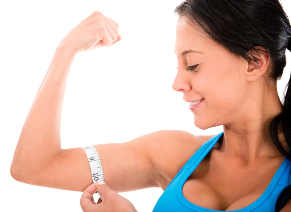 A woman measuring her biceps with a measuring tape to track her progress for arm contouring.