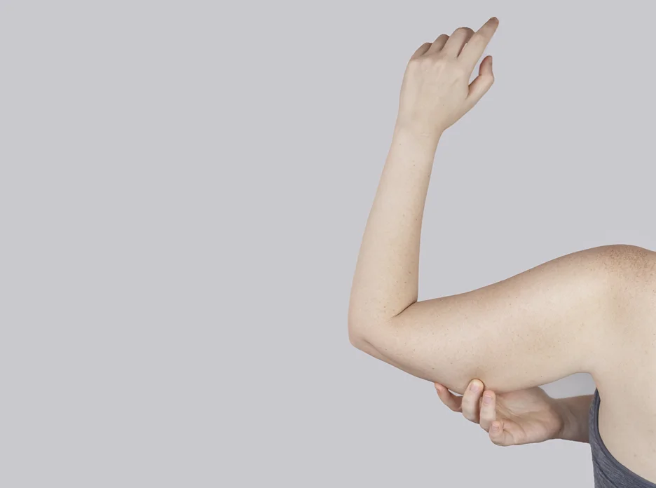 A woman is pointing her arm to the side.