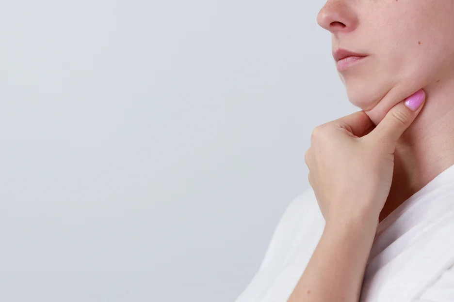 A woman is touching her neck.