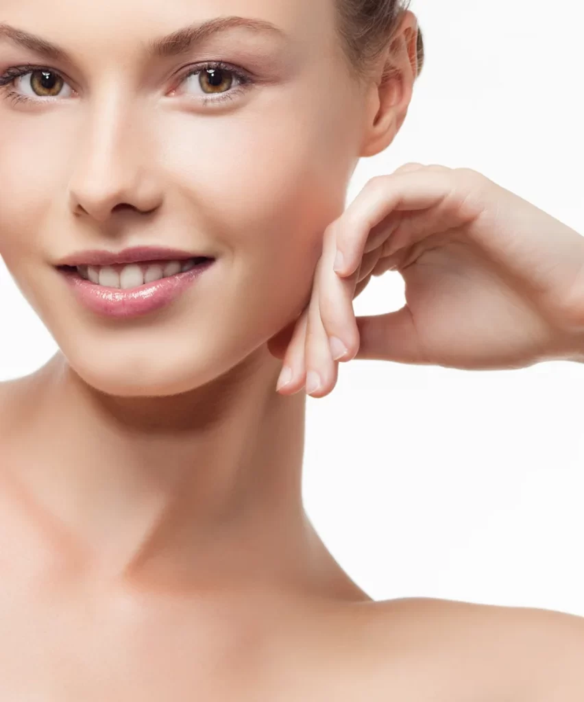A young woman expertly smiling with her hand on her face.