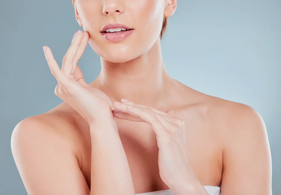 A woman with a defined jawline is touching her face with her hands.