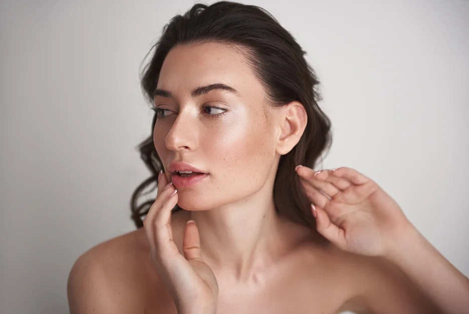A woman is putting her hand on her face, marveling at her sculpted look.